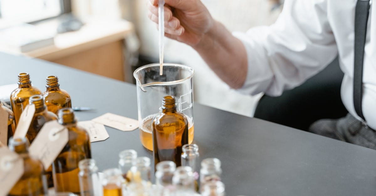 A person blends essential oils in glass bottles for aromatherapy indoors.